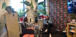 2 vrouwen met elkaar in gesprek in een mooie ruimte met planten